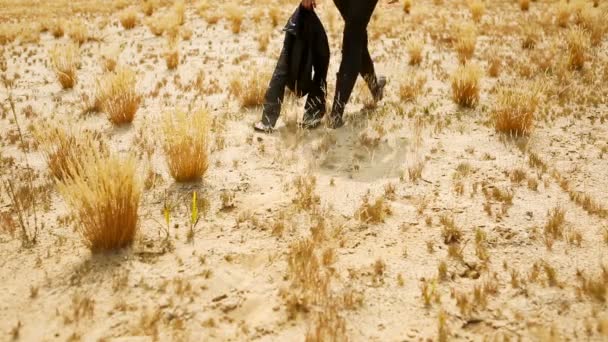 Stijlvolle mooie vrouw in zwart leer jurk lopen over zandwoestijn — Stockvideo