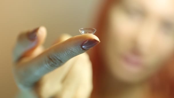 콘택트 렌즈: 눈 앞에서 손가락에 콘택트 렌즈를 들고 있는 젊은 여성 — 비디오