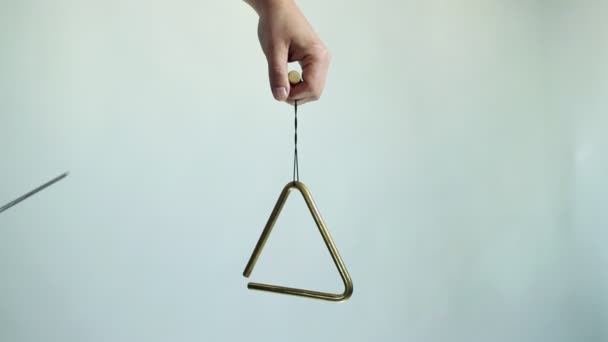 Les mains jouent un triangle musical. Frappez plusieurs fois sur un fond blanc — Video