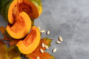 Gri arka planda balkabağı ve balkabağı tohumları. Sonbahar öğle yemeği konsepti. Ahşap bir arka planda. Sağlıklı beslenme ürünü. Boşluğu kopyala.