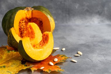 Gri arka planda balkabağı ve balkabağı tohumları. Sonbahar öğle yemeği konsepti. Ahşap bir arka planda. Sağlıklı beslenme ürünü. Boşluğu kopyala.