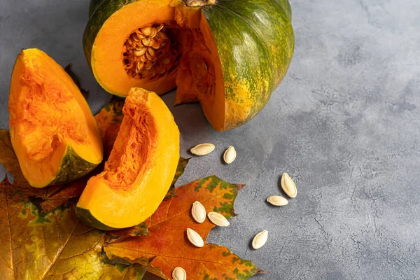 Gri arka planda balkabağı ve balkabağı tohumları. Sonbahar öğle yemeği konsepti. Ahşap bir arka planda. Sağlıklı beslenme ürünü. Boşluğu kopyala.