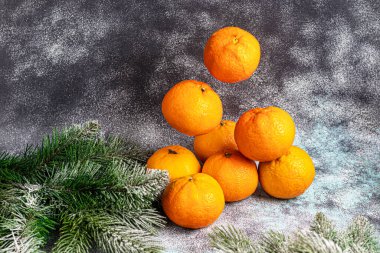 Noel ağacının dalları ve karla kaplı çam kozalakları olan gri bir zemin üzerinde mandallar. Yeni yıl konsepti. Boşluğu kopyala.