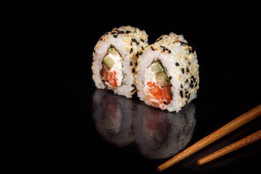 Suşi, Uramaki, California, Philadelphia 'yı beyaz bir tabağa koyar. Şenlikli, yeni yıl konsepti. Karanlık bir arka plana karşı. Boşluğu kopyala