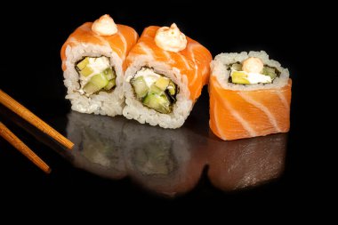 Suşi, Uramaki, California, Philadelphia 'yı beyaz bir tabağa koyar. Şenlikli, yeni yıl konsepti. Karanlık bir arka plana karşı. Boşluğu kopyala