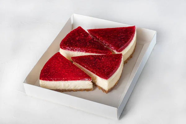 Hafif arka planda cheesecake. Üstünde ahududu reçeli var. Eve teslim. Şenlik konsepti. Karantinaya alın. Boşluğu kopyala.