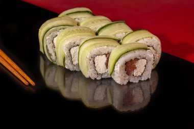 Suşi, Uramaki, California, Philadelphia 'yı beyaz bir tabağa koyar. Yeni yıl kutlaması konsepti. Karanlık bir arka plana karşı. Boşluğu kopyala.