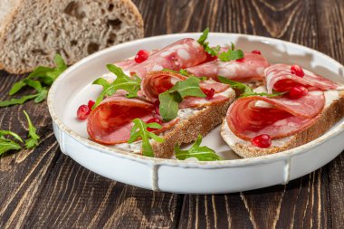 Tabakta füme sosis ve krem peynirli sandviç. Dereotlarıyla süslenmiş. Koyu bir ahşap arka planda.