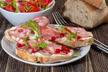 Tabakta füme sosis ve krem peynirli sandviç. Dereotlarıyla süslenmiş. Koyu bir ahşap arka planda.