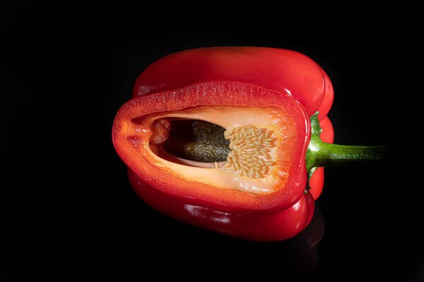 Красный перец в порез на черном фоне. Изолировать. Передний план.