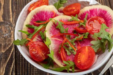 Ispanaklı salata, roka turpu, soğan ve vişneli domates. Pastırmalı sandviç. Kahverengi arka planda.