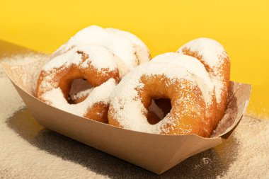 Kağıt tabağa pudra şekeri serpiştirilmiş çörekler. Paket yemek. Renkli arka plan. Boşluğu kopyala.