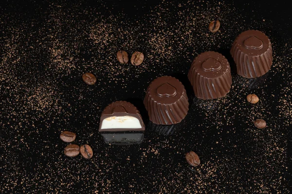 Dulces de chocolate sobre un fondo oscuro con reflejo. Pieza por pieza y como un todo. Relleno de frutos secos y frutas. — Foto de Stock