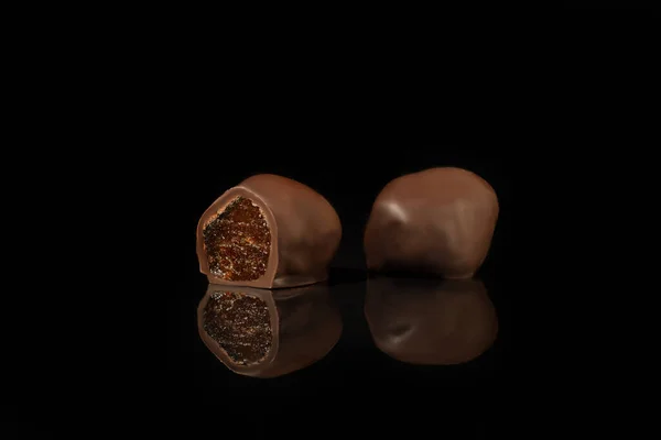 Шоколадні цукерки на темному тлі з відображенням. Шматок за шматочком і в цілому. Начинка з горіхів і фруктів . — стокове фото