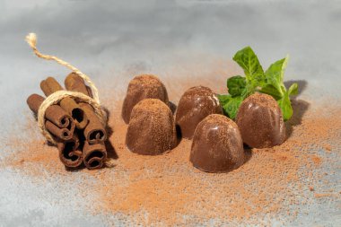 Gri arka planda yansımalı çikolata şekerleri. Parça parça ve bir bütün olarak. Fındık ve meyve dolu. Boşluğu kopyala.