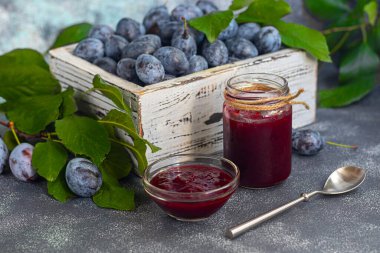 Kavanozda erik reçeli. Arka planda erikler var. Tkemali sosu. Kış için hazırlanıyorum. Hafif arkaplan. Boşluğu kopyala.