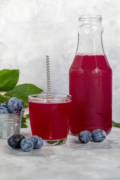 Plum compote in a glass. In the background there are plums. Tkemali sauce. Getting ready for winter. Light background. — Stock Photo, Image