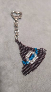 Çizgi film karakteri şekilli anahtarlık. Gri arkaplandaki çok renkli tohum boncukları ve cam boncuklardan yapılmış. Ürün gösterisi.