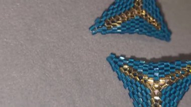 Boncuk ve cam boncuklardan yapılmış el yapımı üçgen küpeler, mavi ve altın sarısı. Boşluğu kopyala.