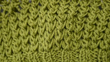 Örgü deseni kalın, yeşil iplik kullanıyor. Örgü kazakları, şapkalar ve diğer örgü eşyalar için detaylar. El Sanatları.
