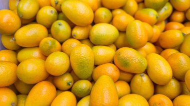 Sarı oval kumkatlar mağaza raflarındaki büyük kutularda. Satılık egzotik meyveler. Süpermarketteki müşterilere ürün tanıtımı.