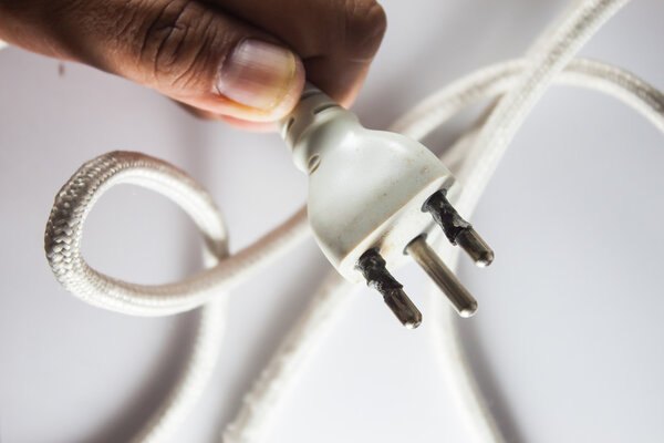 the man hand hold the Plug form the iron burns overload