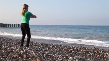 Genç kadın sahilde egzersizleri yapıyor