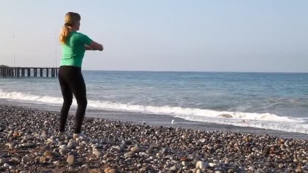 Jovem está fazendo exercícios na praia — Vídeo de Stock