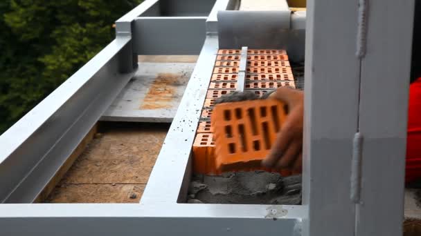 Строитель кладет кирпичи на стройплощадку — стоковое видео