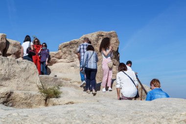 UCHISAR, TURKEY - 4 Ekim 2020: Kimliği belirsiz insanlar tuff kayasının tepesine tırmanır (Uchisar Kalesi).
