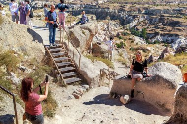 UCHISAR, TURKEY - 4 Ekim 2020 Uchisar Kalesi 'nin tepesindeki kimliği belirsiz insanlar manzaralara hayran ve hatırlamak için fotoğraf çekiyorlar..
