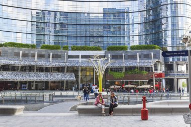 MILAN, ITALY - 17 Mayıs 2018: Kimliği belirsiz insanlar Gae Aulente Meydanı 'ndaki modern yüksek binalarla çevrili çeşmelerin yanında dinleniyor.