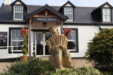 GRETNA GREEN, GREAT BRITAIN - SEPTEMBER 13, 2014: This is a sculpture of a musician playing an accordion in the center of the famous Scottish wedding village. clipart