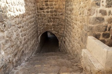 MARDIN, TURKEY - 10 Ekim 2020 Eski kasabadaki evlerin altında bir kemer ve tünel ile dar bir yaya merdiveni caddesi.