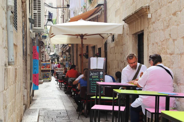 DUBROVNIK, CROATIA - SEPTEMBER 8, 2016: This is one of the narrow side streets of the old city with cafe tables and souvenir shops on it.