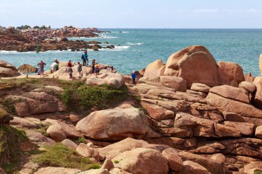 PLOUMANACH, FRANCE - 5 Eylül 2019 Brittany 'deki Pembe Granit Sahili' ndeki alışılmadık renkli granit kayalar üzerinde bir grup insan..