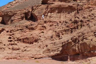 ELIFAZ, ISRAEL - 22 EPTEMBER 2017: Kimliği belirsiz genç bir adam Arava Çölü 'ndeki Timna Ulusal Doğa Koruma Alanındaki aşınmış bir uçurumun yamacına tırmandı.