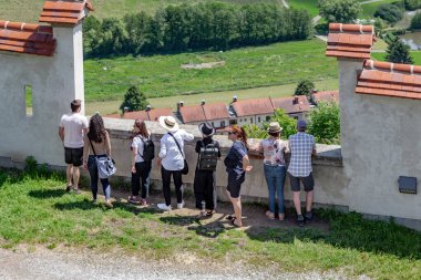 RIEGERSBURG CASTLE, AUSTRIA - 18 Mayıs 2024: Bir grup tanımlanamayan turist kaleye giden güçlendirilmiş yolun duvarındaki özel bir gözlem noktasından çevreye hayran.