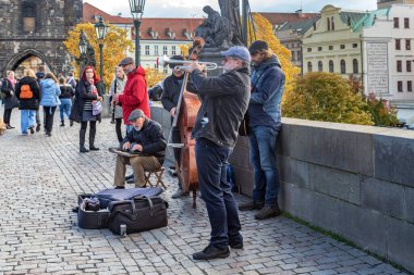 PRAGA, CZECH - 26 Ekim 2023: Charles Köprüsü 'nden geçenler için kimliği belirsiz müzisyenler gösteri yapıyor.