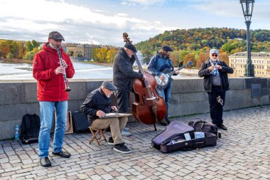 PRAGA, CZECH - 26 Ekim 2023: Charles Köprüsü 'nden geçenler için kimliği belirsiz müzisyenler gösteri yapıyor.