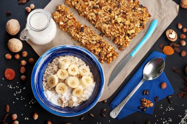. Yulaf ezmesi, meyveler, kurutulmuş meyveler ve kuruyemişler ile koyu bir yüzeyde granola ve lezzetli kahvaltı. Fındık, ceviz, kuru üzüm ve kuru kayısı gibi granola hazırlanması için malzemeler yanında