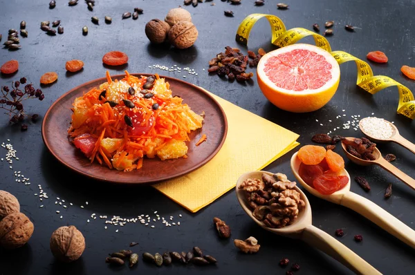 Comida de dieta de conceito. Salada leve com cenoura, laranja e toranja. Ao lado de frutas secas e nozes, que são usadas na preparação de uma dieta equilibrada. Comida vegetariana saudável . — Fotografia de Stock