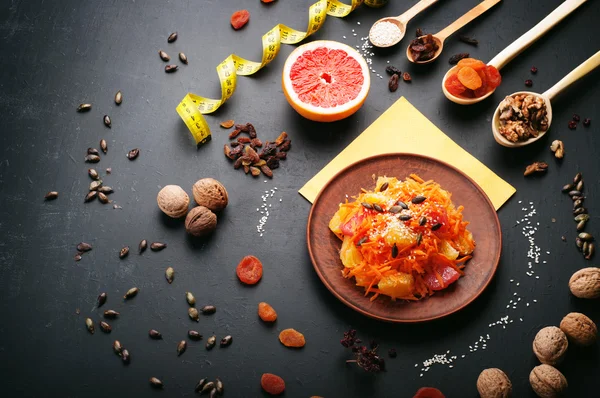 Comida de dieta de conceito. Salada leve com cenoura, laranja e toranja. Ao lado de frutas secas e nozes, que são usadas na preparação de uma dieta equilibrada. Comida vegetariana saudável . — Fotografia de Stock