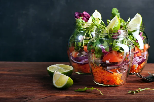 Salata arugula, havuç, domates, mor soğan ve limon ile cam bir kavanozda. Eğer bir cam kavanozda çalışmak için yanınıza alabilir sağlıklı gıda ev pişirme, kavramı. Vejetaryen salatası. Faydalı diyet yemeği.