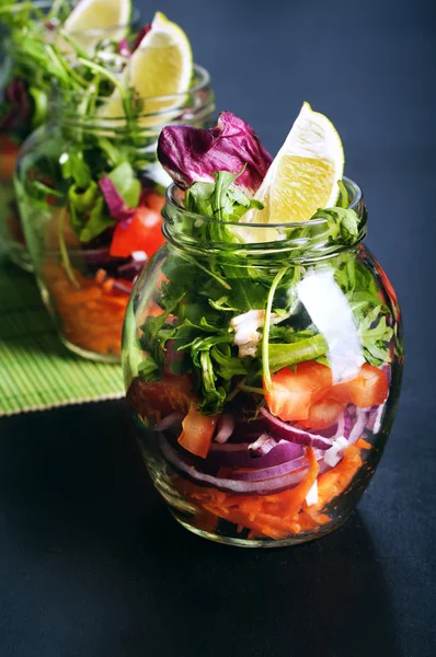 Das Konzept einer gesunden Ernährung. leichter Salat aus Rucola, Tomate, lila Zwiebel und Limette, den man zum Arbeiten in ein Glas mitnehmen kann. Nützliches und schmackhaftes Essen zum Mitnehmen. — Stockfoto