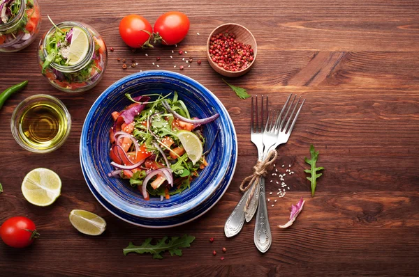 Das Konzept einer gesunden Ernährung. leichter Salat aus Rucola, Tomate, lila Zwiebel und Limette, den man zum Arbeiten in ein Glas mitnehmen kann. Nützliches und schmackhaftes Essen zum Mitnehmen. — Stockfoto