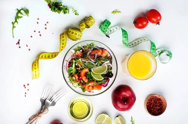 Comida de dieta de conceito. Salada leve de rúcula, tomate, cebola roxa e limão sobre fundo branco. Próximo fita métrica simbolizando a medição do volume corporal durante uma dieta. Comida vegetariana com baixo teor de gordura . — Fotografia de Stock