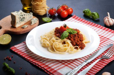 Bolognese makarna beyaz tabakta bir beyaz ve kırmızı bir peçete. Makarna yapma için maddeler. İtalyan mutfağı
