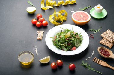 Kavram diyet yiyecek. Roka, salatalık dilimleri ve karanlık bir yüzey üzerinde bir greyfurt salatası. Greyfurt ve yumurta ile klasik diyet bir varyasyonu.