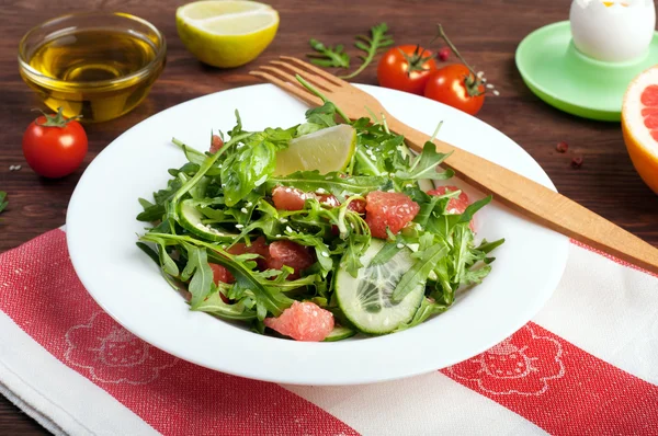 Konzept Diät Nahrung. Salat mit Rucola, Gurkenscheiben und einer Grapefruit auf dunkler Oberfläche. Eine Variante der klassischen Ernährung mit Grapefruit und Eiern. brauner Holzhintergrund — Stockfoto